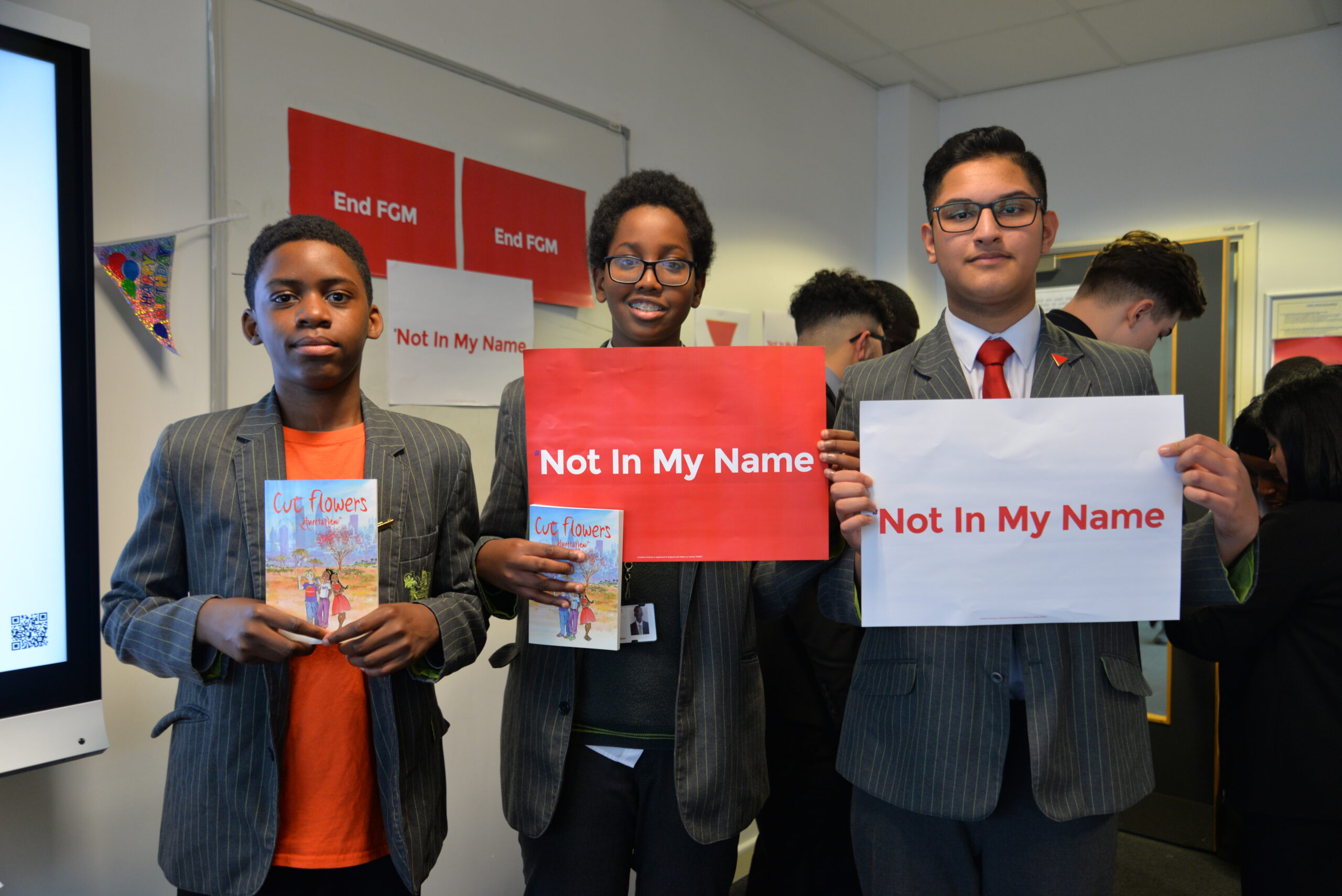 Young men holding Not in My Name and End FGM campaign banners